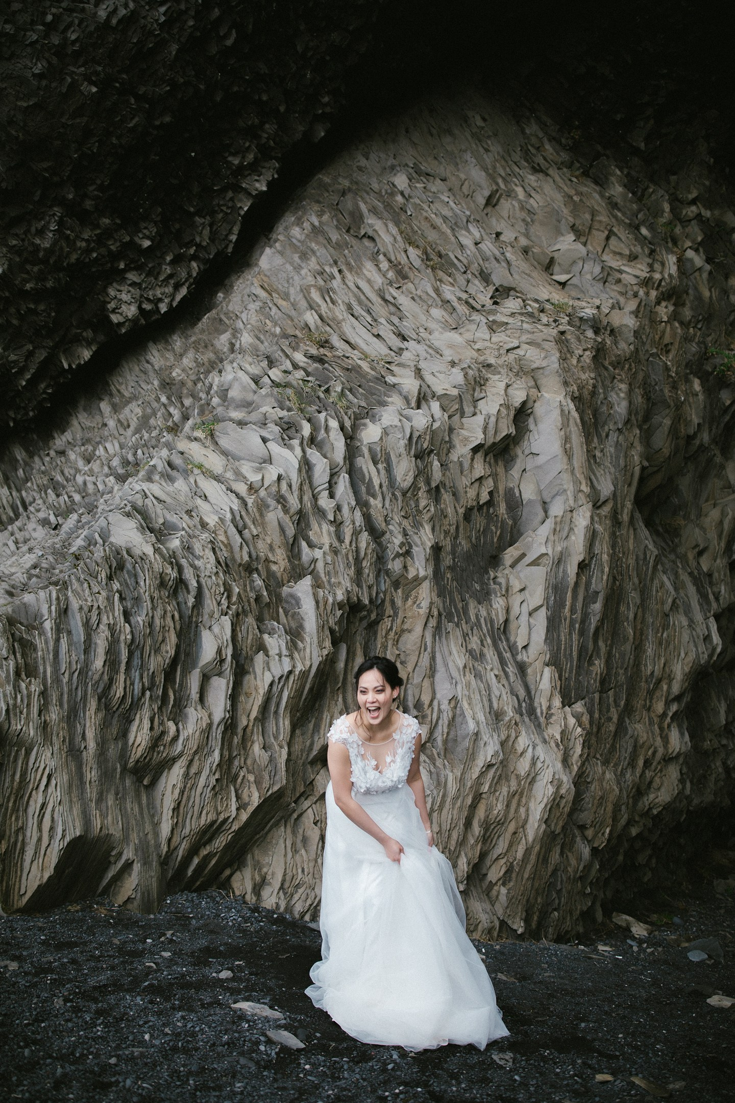 Bride laughing in front of textured cliff – Iceland wedding