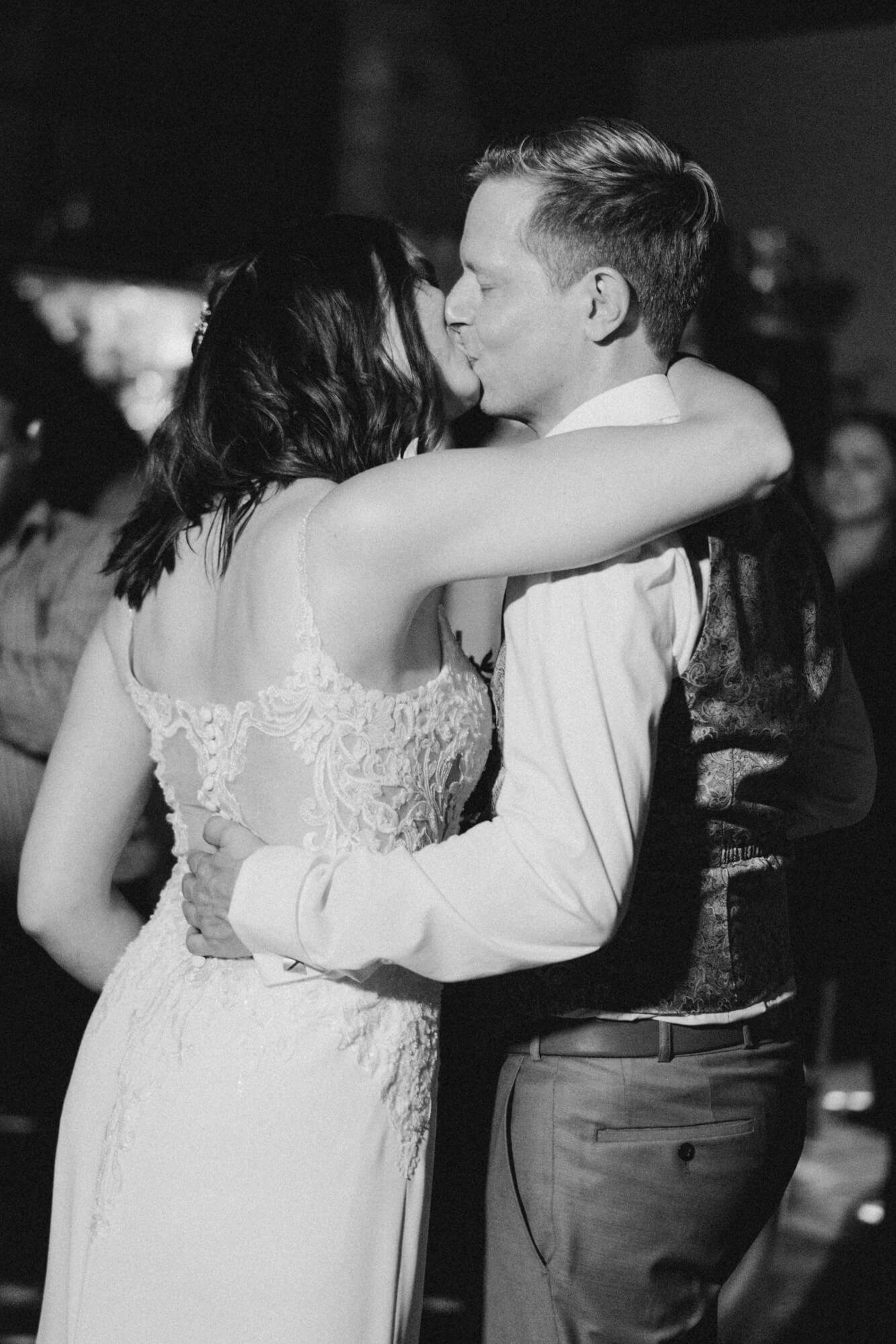 Newlyweds sharing a kiss on the dance floor; black and white