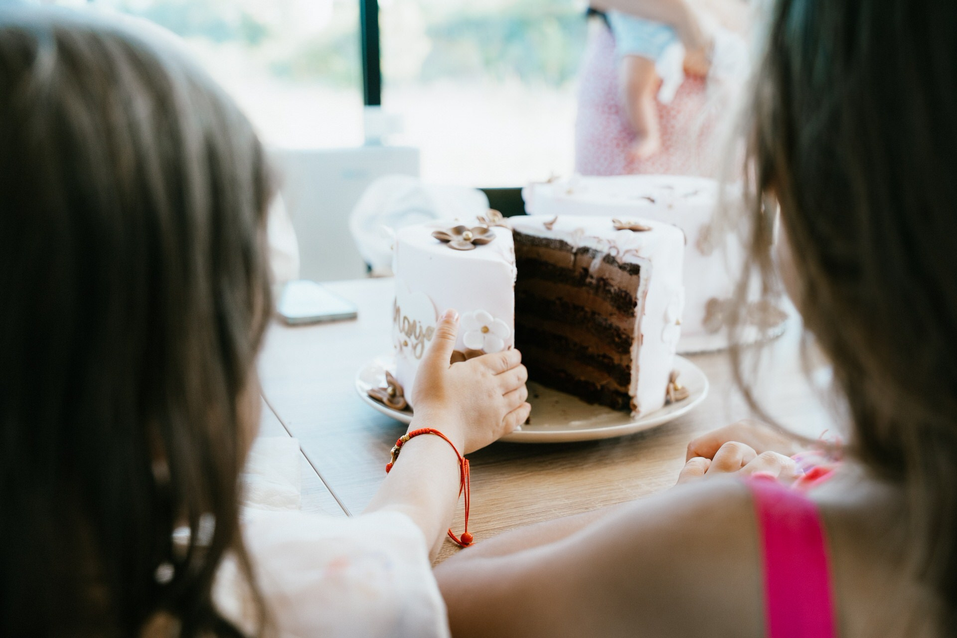kadar načete torte i prstiči dece koji žele da je dotaknu i poližu